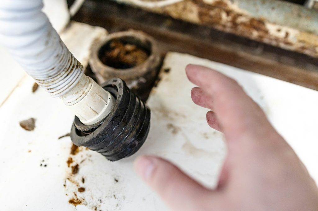 hand of plumber near corrugated drain hose closeup - V-Max Plumbing