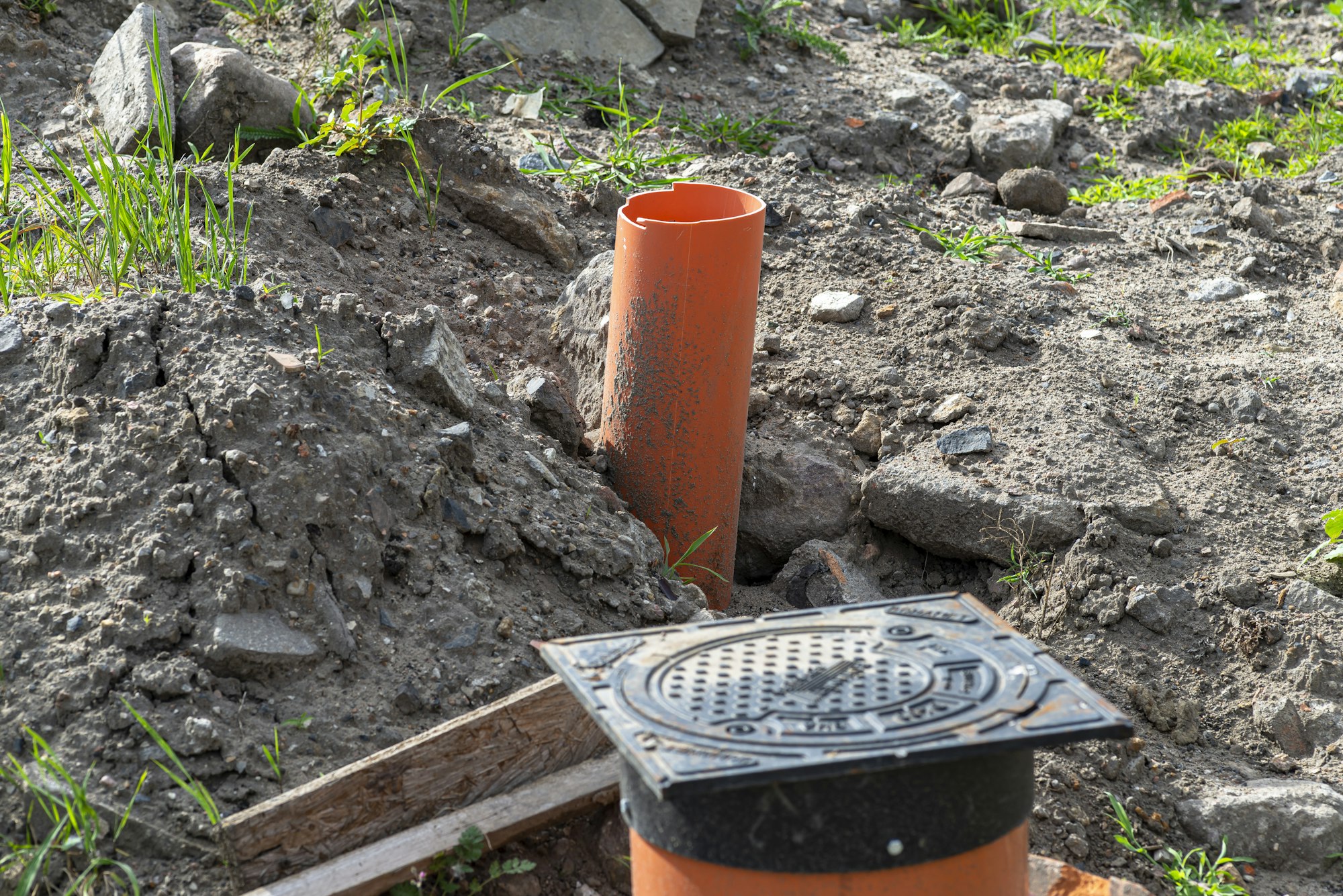 Inspection of the sewage system with a closed cast iron manhole, visible plastic pipes. - V-Max Plumbing