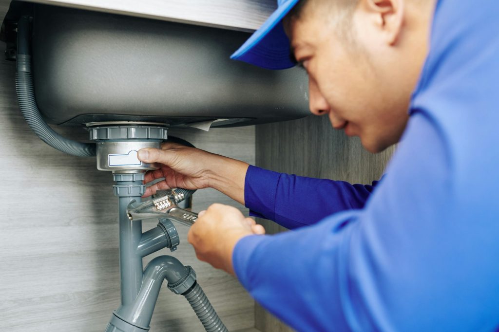 Plumber repairing a leaky drain - V-Max Plumbing