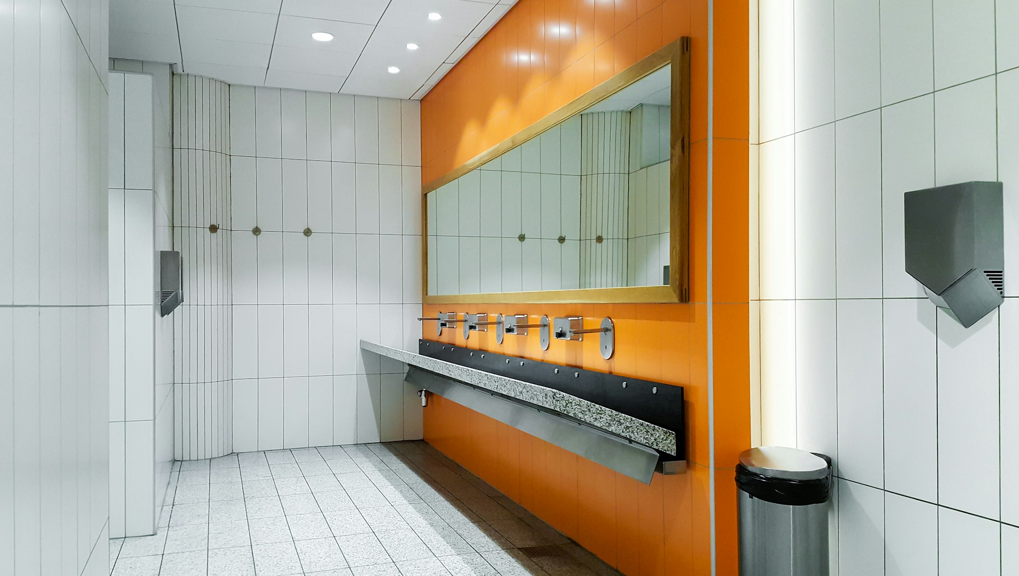 Public empty restroom with washstands mirror by licensed plumbers across the greater Los Angeles area.