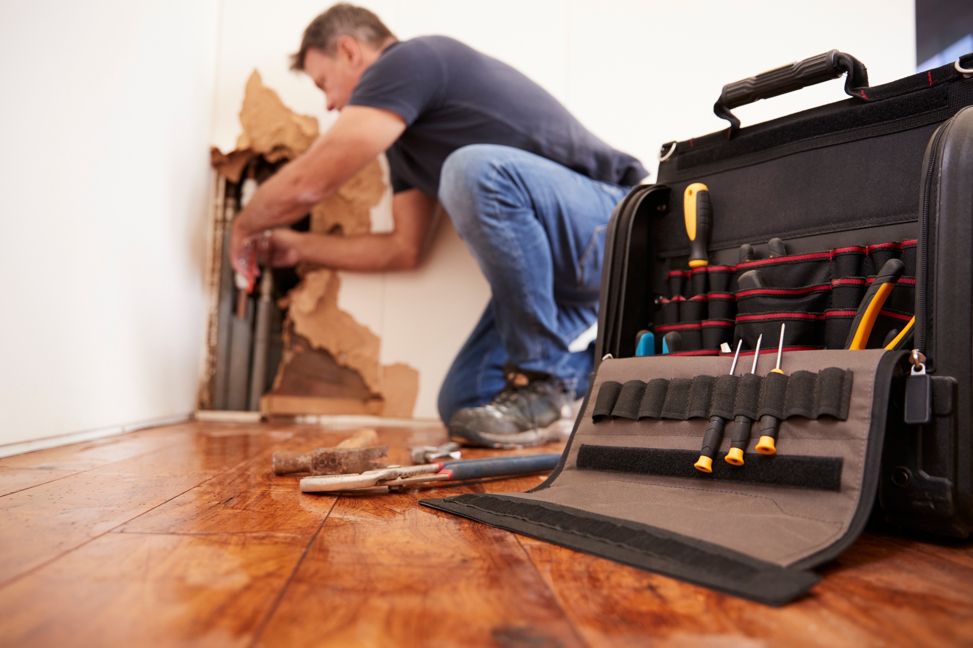 Middle aged man repairing burst pipe,plumbing, focus on foreground